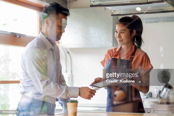 customer paying with contactless payment system - jgalione stock pictures, royalty-free photos & images