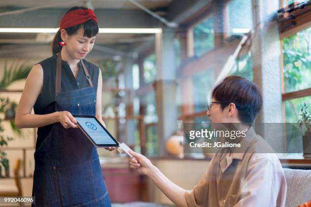 customer paying with contactless payment system in a cafe - jgalione stock pictures, royalty-free photos & images