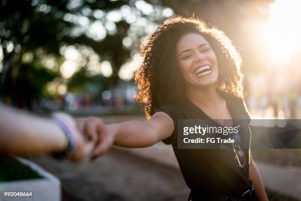 beautiful curly hair woman holding hands/following boyfriend - joy stock pictures, royalty-free photos & images