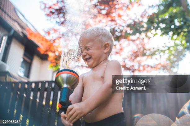 kleiner junge besprühen mit wasser in den kopf - boy taking a shower stock-fotos und bilder