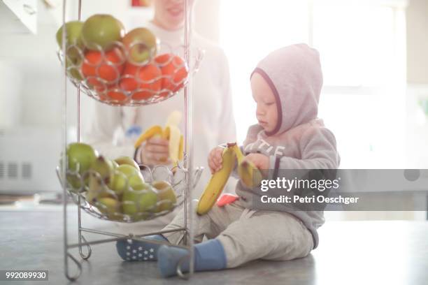 a young mother sharing a banana with her baby. - petri schaal stockfoto's en -beelden