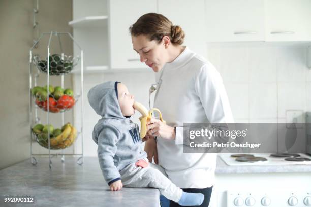 a young mother sharing a banana with her baby. - petri schaal stockfoto's en -beelden