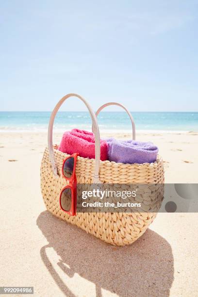 bag with towels and sunglasses on the beach - beach bag stock-fotos und bilder