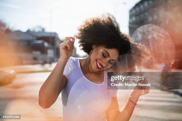 curly haired young woman dancing on street - swaying stock pictures, royalty-free photos & images