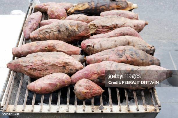 sweet potato roasted just taken from the gridiron. - gridiron dinner stockfoto's en -beelden
