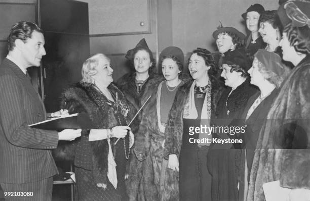 Welsh actor and composer Ivor Novello watches his mother, singer Clara Novello Davies conduct the Welsh Ladies' Choir in a rehearsal for the show...