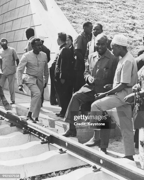 President Kenneth Kaunda of Zambia and President Julius Nyerere of Tanzania rest their feet on the sleepers of the new Great Uhuru Railway which...