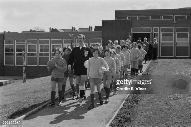English referee Ken Burns with teams who took part in the Ocker Hill Junior School Cup final, Birmingham, UK, 4th May 1973.