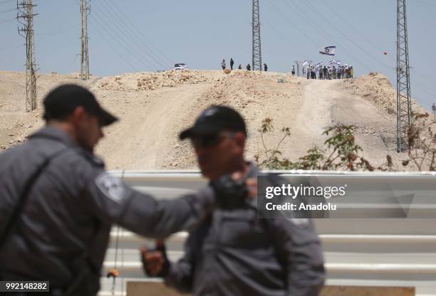 Jewish settlers wave flags and shout slogans while Israeli forces raise security as Palestinians keep watch in Khan al-Ahmar village following...