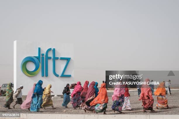 Djiboutian women walk in front of the sign board of Djibouti International Free Trade Zone before an inauguration ceremony in Djibouti on July 5,...