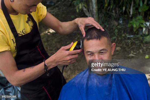 Thai rescue personnel receives a free haircut from a volunteer at the Tham Luang cave area as operations continue for 12 boys and their coach trapped...