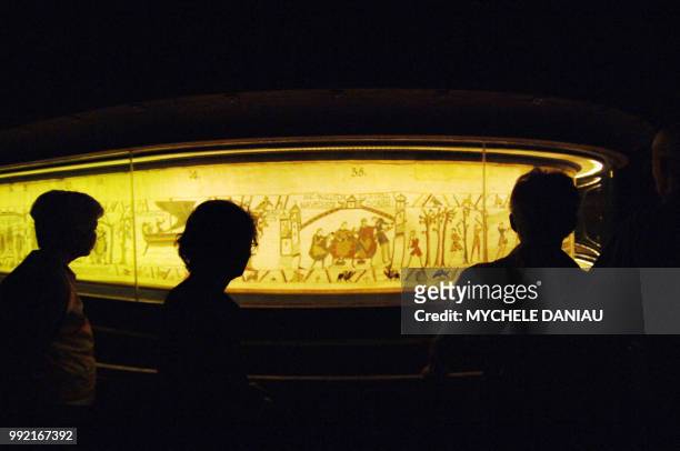 Des visiteurs observent la tapisserie de Bayeux le 27 août 2007 au musée de la tapisserie de la ville. Cette broderie du 11ème siècle est inscrite...