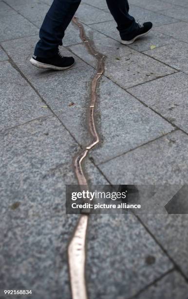 People walk over a 'crack' made of bronze on the ground at the Kaiser Wilhelm Memorial Church in Berlin, Germany, 24 November 2017. The 15-meter-long...