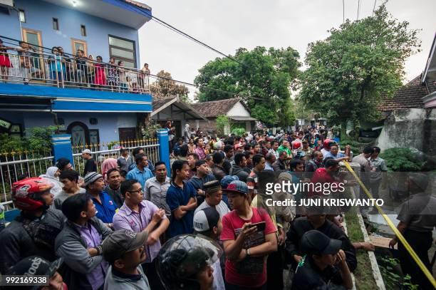Villagers gather in front of a house under police investigation in the city of Bangil, East Java province on July 5 after an alleged terrorist who...
