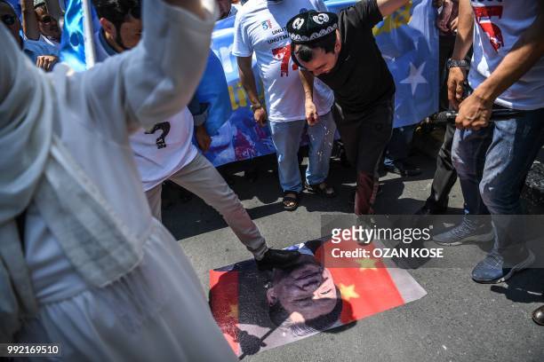 Supporters of the mostly Muslim Uighur minority and Turkish nationalists step on a poster of Chinese President Xi Jinping and Chinese communist...