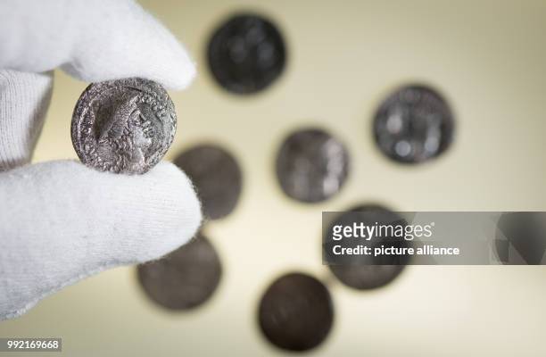 Roman silver coin ) is being held over a light table in the Varusschlacht Museum and Park Kalkriese in Bramsche-Kalkriese, Germany, 22 November 2017....