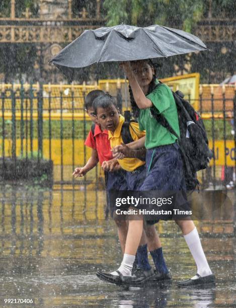 Kids hold umbrella as it rain at CSMT, on July 4, 2018 in Mumbai, India. Heavy rains made a comeback in Mumbai causing waterlogging in many parts of...