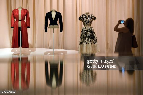 Visitor takes a picture with her smartphone Gala's dresses "Long coat, open at the front from top the botton" , "Night's jacket" and " Blouse and...