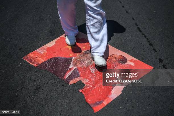 Demonstrator steps on a poster of Chinese President Xi Jinping and Chinese communist leader Mao Zedong during a protest of the mostly Muslim Uighur...