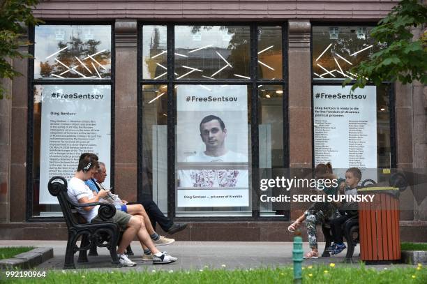 People rest in front of a poster with a photo of Ukrainian film director Oleg Sentsov, taken by journalist Anton Naumlyuk, displayed in the shop...