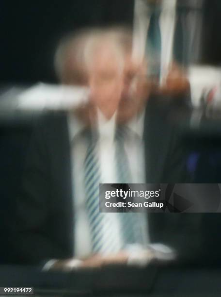 German Interior Minister and leader of the Bavarian Social Union , Horst Seehofer, is seen through two sections of glass as he attends debates at the...
