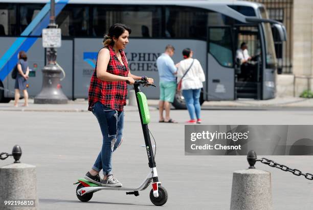 Woman rides an electric scooter Lime-S from the bike sharing service company "Lime" on July 05, 2018 in Paris, France. The American start-up Lime,...