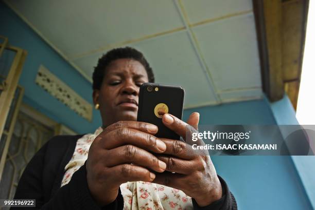 Woman reads messages on her Apple iphone in Kampala on July 5, 2018. - Politicians, clerics, feminists and others have formed a broad coalition of...