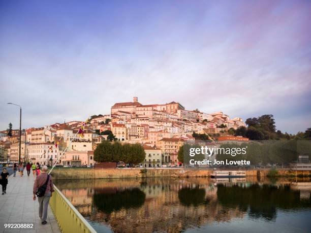 mondego river and coimbra with people crossing bridge at sunset - mondego stock pictures, royalty-free photos & images