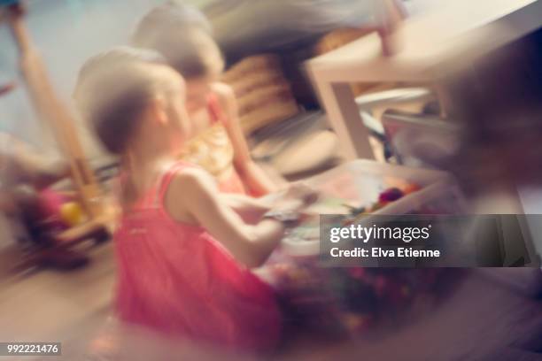 two girls looking at toys in a toy box and shot through a curved glass object - distorted stock pictures, royalty-free photos & images