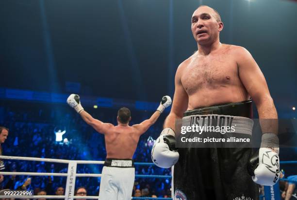 Russian Alexander Ustinov walks disappointed across the boxing ring while German Manuel Charr celebrates in the background after the WBA World...