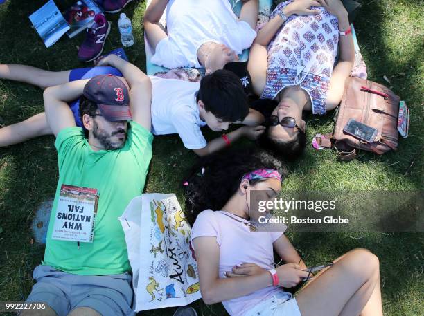 Jose Hernandez, left, and his wife, Daniella, right, relax in the shade with their children Carlos Santi and Ana while waiting for the Boston Pops...