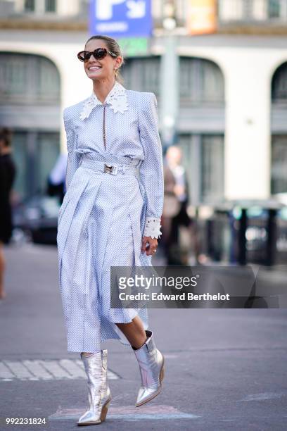 Helena Bordon wears a white and blue dress with a shirt collar, a blue bag, silver shiny boots, sunglasses, outside Fendi, during Paris Fashion Week...