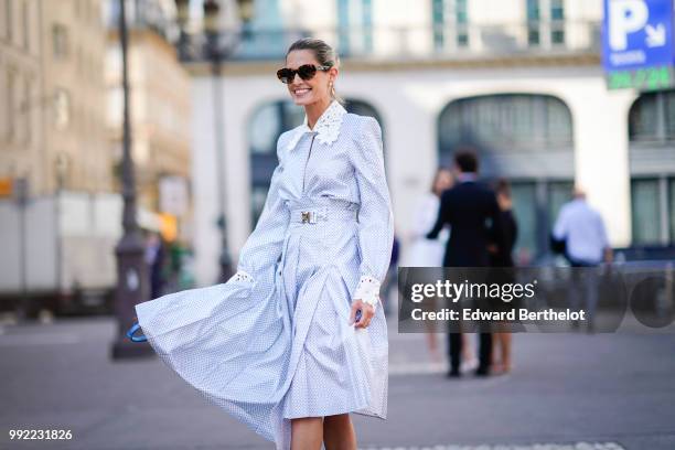 Helena Bordon wears a white and blue dress with a shirt collar, a blue bag, silver shiny boots, sunglasses, outside Fendi, during Paris Fashion Week...