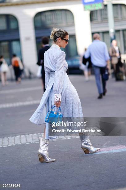 Helena Bordon wears a white and blue dress with a shirt collar, a blue bag, silver shiny boots, sunglasses, outside Fendi, during Paris Fashion Week...