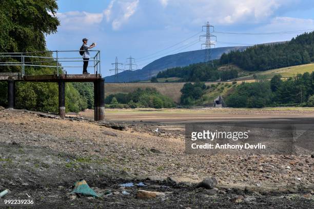 Man photographs the low water levels in Bottoms Reservoir, one of the Longendale Reservoirs near Tintwistle in the High Peak on July 5, 2018 in...