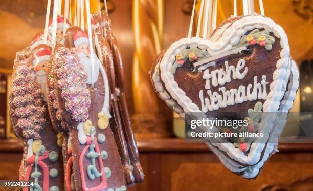 Gingerbread figures and hearts with the lettering 'Frohe Weihnachten' hang in a stand of the Roncalli Christmas market at the Rathausmarkt square in...