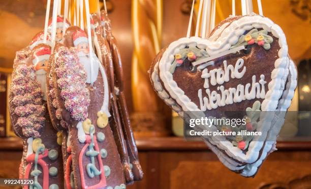 Gingerbread figures and hearts with the lettering 'Frohe Weihnachten' hang in a stand of the Roncalli Christmas market at the Rathausmarkt square in...