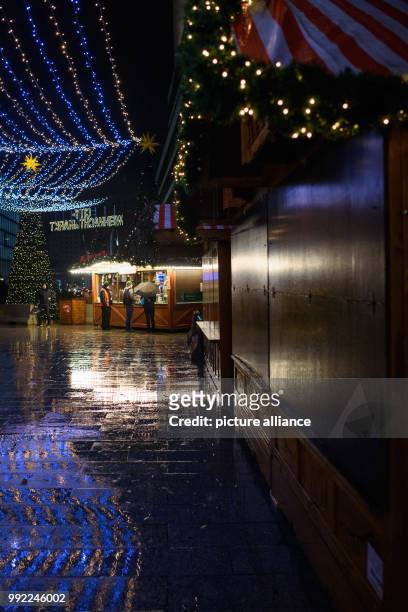 The last visitors standing during rainy weather at one of the last open stalls of the Christmas market at Breitscheidplatz in Berlin, Germany, 27...