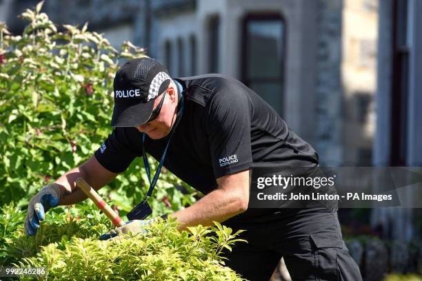 Police officer searches a garden in Ardbeg Road on the Isle of Bute in Scotland, after the body of Alesha MacPhail was found in woodland on the site...