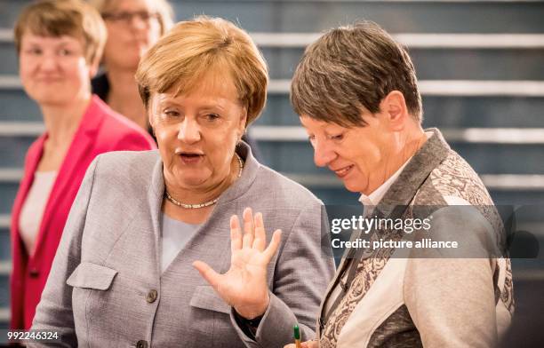 German Environment Minister Barbara Hendricks speaks with German Chancellor Angela Merkel as they arrive to attend the 'Diesel Summit' with mayors of...