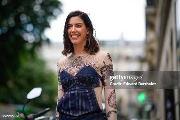 Camila Coutinho wears a blue denim corset, a lace mesh top with embroidered flowers, blue denim jeans, outside Jean-Paul Gaultier, during Paris...