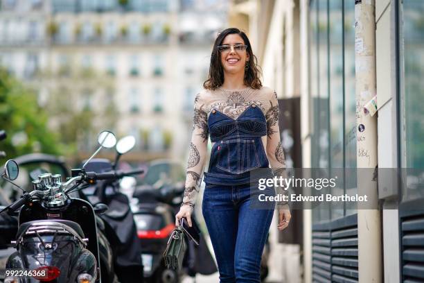 Camila Coutinho wears a blue denim corset, a lace mesh top with embroidered flowers, blue denim jeans, outside Jean-Paul Gaultier, during Paris...