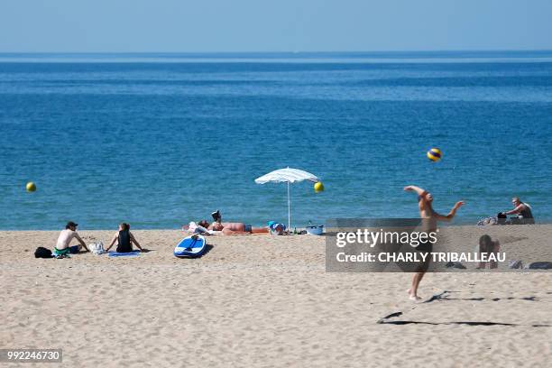 People sun bath on the beach on July 5, 2018 in Ouistreham, northwestern France