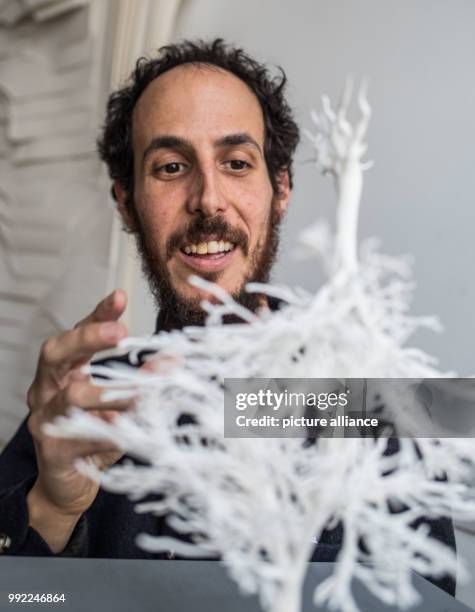 The Israeli artist currently residing in Mexico, Ariel Schlesinger, standing behind a 3D print-out of his planned sculpture, which will be composed...