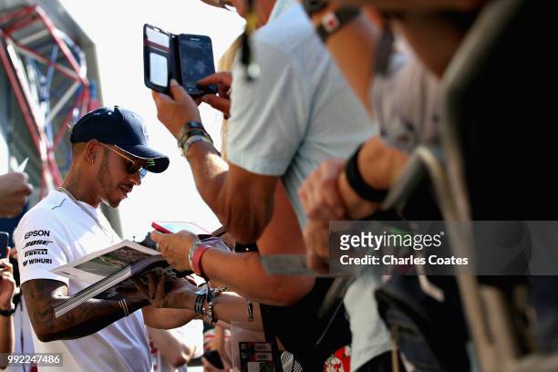 Lewis Hamilton of Great Britain and Mercedes GP signs autographs for fans during previews ahead of the Formula One Grand Prix of Great Britain at...