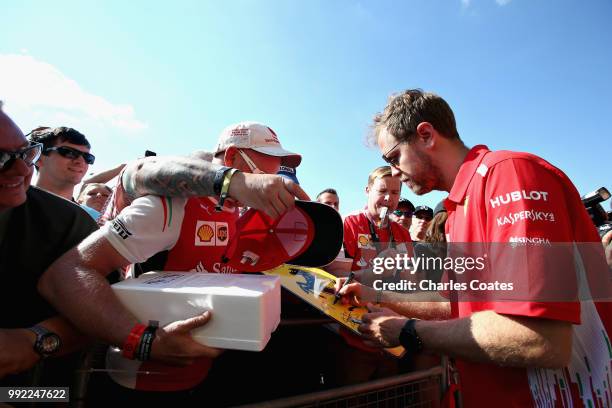 Sebastian Vettel of Germany and Ferrari signs autographs for fans during previews ahead of the Formula One Grand Prix of Great Britain at Silverstone...