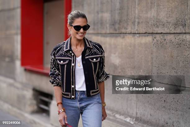 Helena Bordon wears a jacket with shiny embroidery, a white top, ripped jeans, a bag, outside Elie Saab, during Paris Fashion Week Haute Couture Fall...