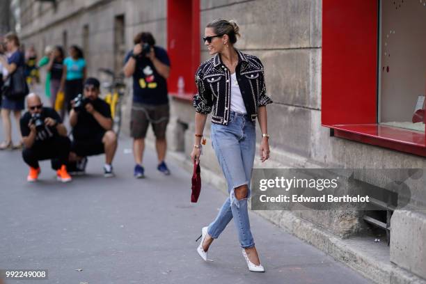 Helena Bordon wears a jacket with shiny embroidery, a white top, ripped jeans, a bag, outside Elie Saab, during Paris Fashion Week Haute Couture Fall...