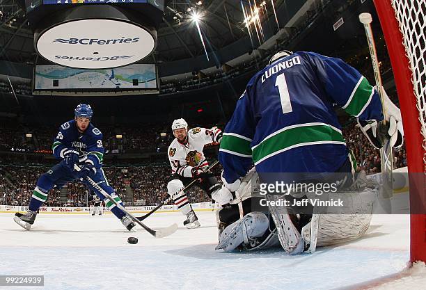 Shane O'Brien of the Vancouver Canucks and Adam Burish of the Chicago Blackhawks look for a rebound in front of Roberto Luongo of the Vancouver...