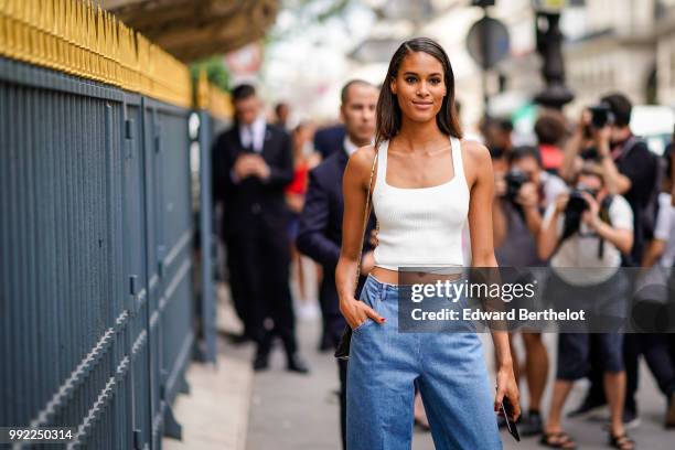 Model Cindy Bruna wears a white tank top, cropped blue jeans, white sneakers shoes , outside Elie Saab, during Paris Fashion Week Haute Couture Fall...